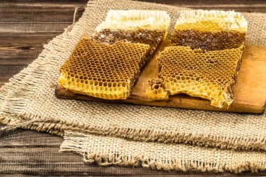 Jüt tutuyordu, seçici odak ile peteğin rustik ahşap zemin üzerine bal ile kaplı.