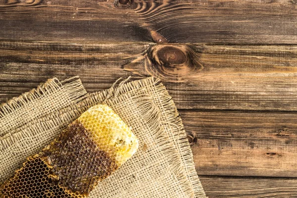 Jüt tutuyordu, üstten görünüm ile peteğin rustik ahşap zemin üzerine bal ile kaplı.