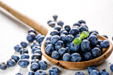 Beyaz arka planda yaban mersinli ahşap kaşık