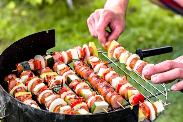 야채와 소시지 꼬치를 준비 하는 손 음식 바베 큐 그릴에 굽고, 잔디, 여름에 밖에 서 바베 큐 파티 개념 — 스톡 사진