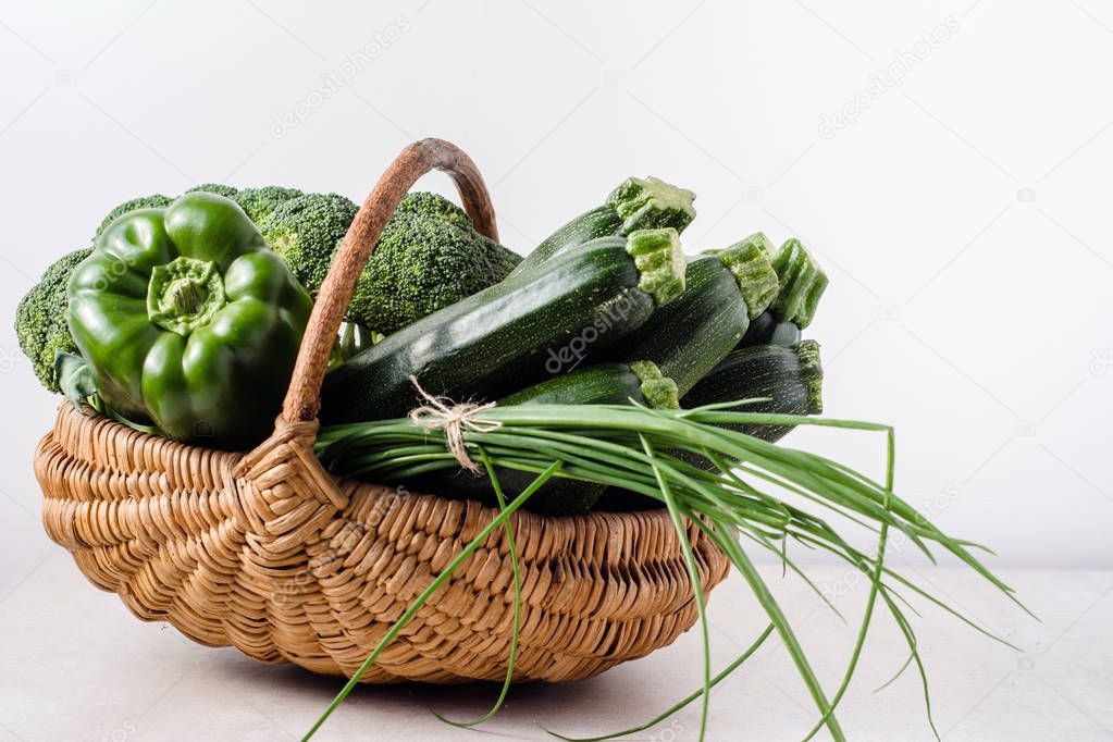 Green vegetables in the basket, local farmer market with assorted produce isolated on white background