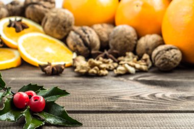 Geleneksel Noel baharat ve holly, yıldız anason, portakal ve fındık ile rustik ahşap arka plan üzerinde meyve