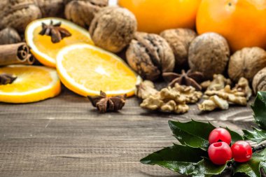 Geleneksel Noel baharat ve holly, yıldız anason, portakal ve fındık ile rustik ahşap arka plan üzerinde meyve