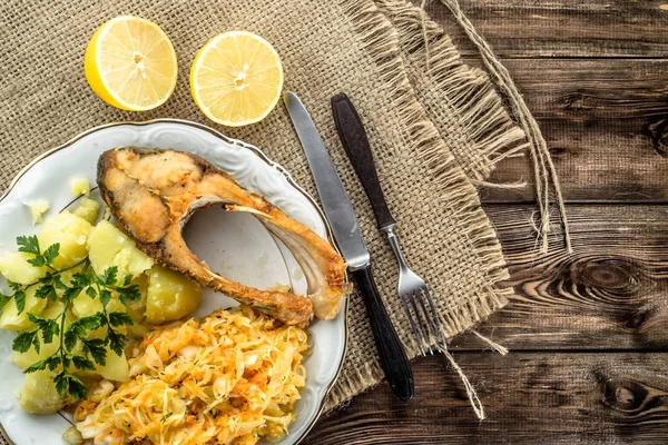 Жареная рыба с салатом и картошкой, традиционный ужин на тарелке, кулинарная концепция — стоковое фото