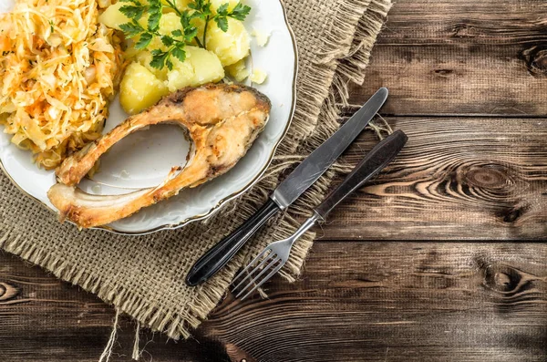 Жареная рыба с салатом и картошкой, традиционный ужин на тарелке, кулинарная концепция — стоковое фото
