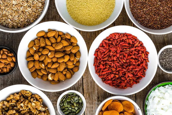 Ingredientes de desayuno saludable con superalimentos en la mesa, semillas, frutas, cereales, nueces, almendras, bayas de goji, alimentos saludables, puesta plana, gastos generales — Foto de Stock