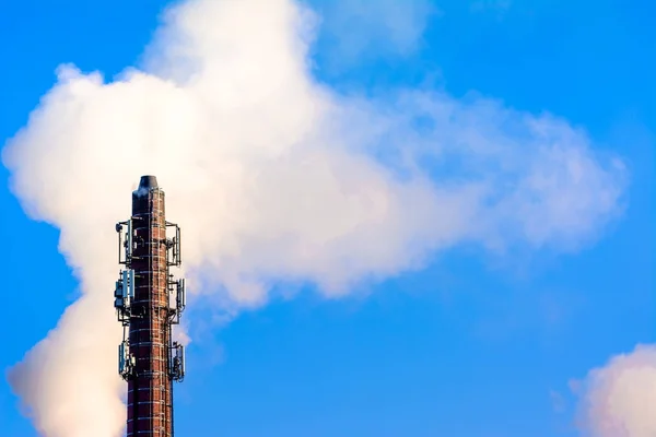 Elektriciteitscentrale schoorsteen met koolstof uitstoot - kooldioxide, co2 en fossiele brandstoffen. Luchtverontreiniging door de industrie. Schoorsteen en rook wolk op blauwe hemelachtergrond. — Stockfoto