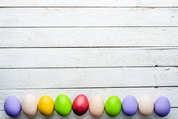Fondo de Pascua, huevos de Pascua pintados de colores estacionales en tablas blancas de madera — Foto de Stock