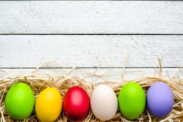 Fondo de Pascua, huevos de Pascua pintados de colores estacionales en tablas blancas de madera — Foto de Stock
