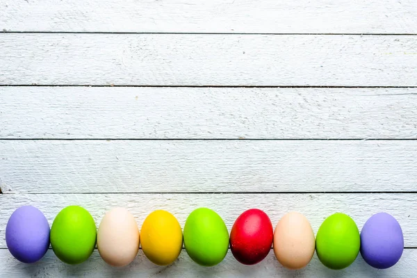 Huevos de Pascua sobre fondo de madera, pizarras blancas con grupo de huevos, vista superior — Foto de Stock