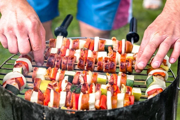 Vegetables and meat kebabs grilled over the coals on barbecue grill, people grilling food outdoors — Stock Photo, Image