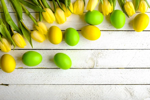 Oeufs de Pâques de printemps sur fond en bois, oeufs et tulipes sur table, frais généraux — Photo