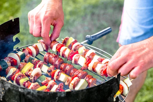 Kebabs de viande de légumes et saucisses grillées sur barbecue, personnes grillades sur herbe, concept de fête d'été — Photo