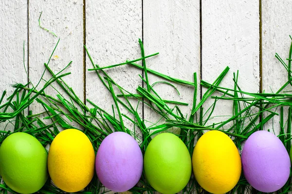 愉快的复活节彩蛋在木背景, 五颜六色的蛋在白色板 — 图库照片