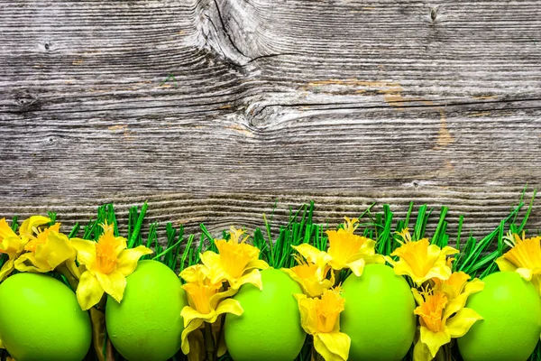 Fond en bois avec oeufs de Pâques et jonquilles — Photo