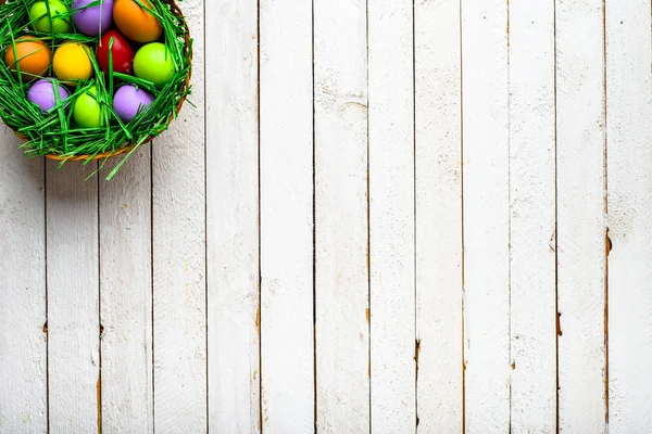 篮子与复活节彩蛋, 背景以五颜六色的蛋, 春天节日装饰在木背景 — 图库照片