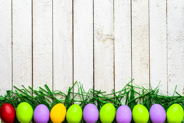 Felices huevos de Pascua sobre fondo de madera, huevos coloridos sobre pizarras blancas — Foto de Stock