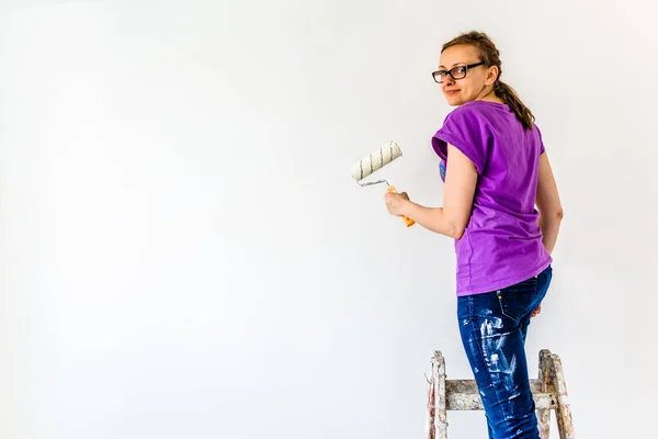 Woman painter working on house renovation. Painting wall with paint brush.