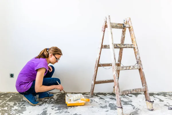 Woman painting wall, house renovation and working indoors concept