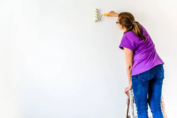 Woman painting wall, house renovation and working indoors concept