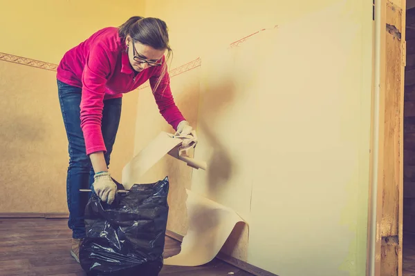 Home renovation, room wall repairing, woman removing old wallpap — Stock Photo, Image