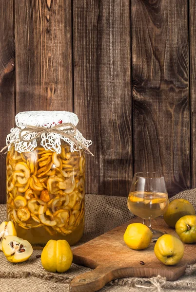 Tarro de licor con frutas de membrillo sobre una mesa de madera —  Fotos de Stock