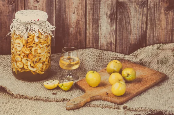 Tarro de licor con frutas de membrillo sobre una mesa de madera —  Fotos de Stock