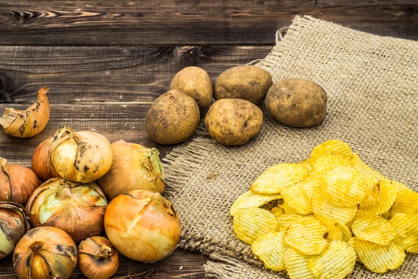 Куча картофельных чипсов со вкусом лука на деревенском джуте и деревянном фоне, мелкая глубина резкости . — стоковое фото