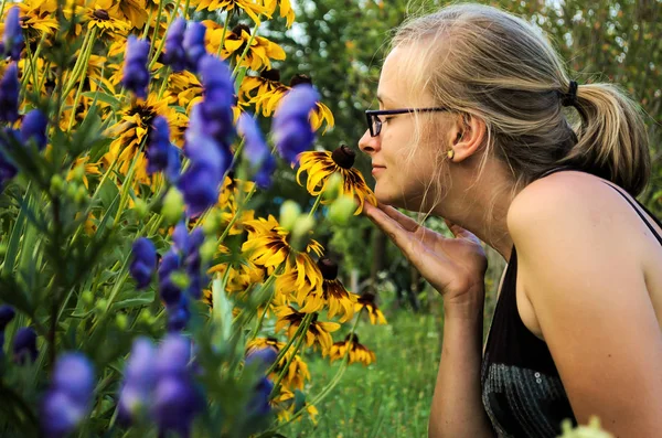정원에서 꽃 냄새맡는 젊은 여자. — 스톡 사진