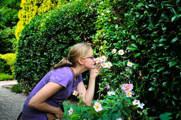 정원에서 꽃 냄새맡는 젊은 여자. — 스톡 사진