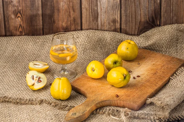 Quince fruits tincture in a glass on a canvas background. — Stock Photo, Image