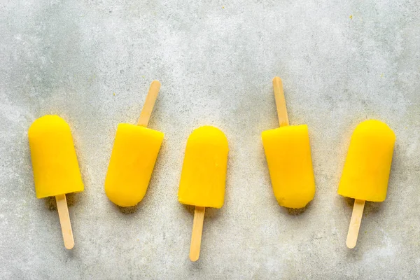 Homemade popsicles with orange juice, ice lollies on sticks, top view flat lay