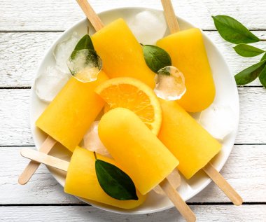 Beyaz ahşap zemin üzerinde turuncu çubuklu dondurmayı. Ev yapımı buz çıkar, en iyi görünüm düz yatıyordu