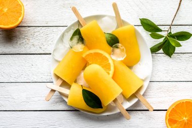 Beyaz ahşap zemin üzerinde turuncu çubuklu dondurmayı. Ev yapımı buz çıkar, en iyi görünüm düz yatıyordu