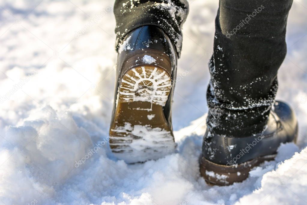 Fashionable male boots in snow, feet in the black shoes hiking in winter