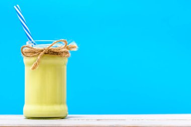 Sağlıklı avokado güler yüzlü, organik iç mavi zemin üzerine kavanoz içinde