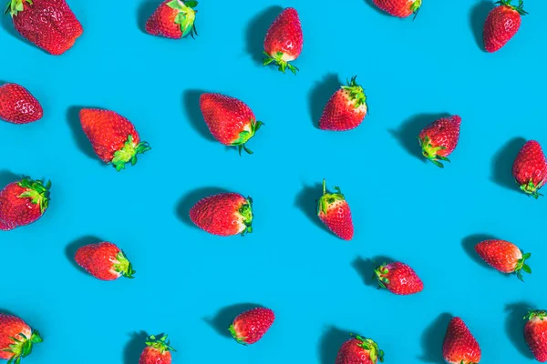 Fresh strawberries pattern, strawberry fruit on blue background, minimal creative food concept