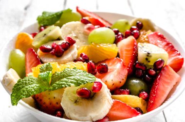 Karışık meyve salatası, closeup Beyaz ahşap zemin, temiz yemek ve sağlıklı gıda kavramı