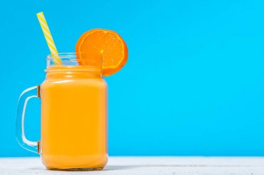 Portakallı gazoz meyve veya tropikal kavanoza karışık meyve kokteyli ile mavi arka plan üzerinde içmek