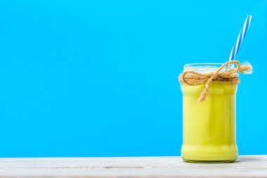 Mavi arka plan, sağlıklı avokado kokteyl bardağı taşıran damla kavanoza üzerinde yeşil smoothie