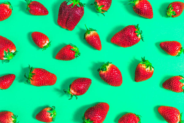 Colorful fruit pattern of strawberries on green background, flat lay, overhead