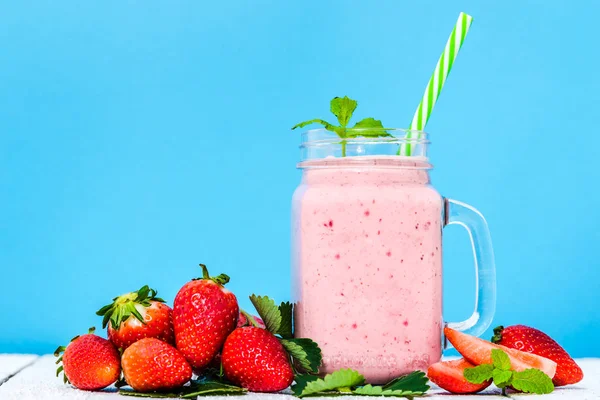 Frukt milkshake med jordgubbar, burk smoothie med dessert jordgubb blandat i burk på blå bakgrund — Stockfoto