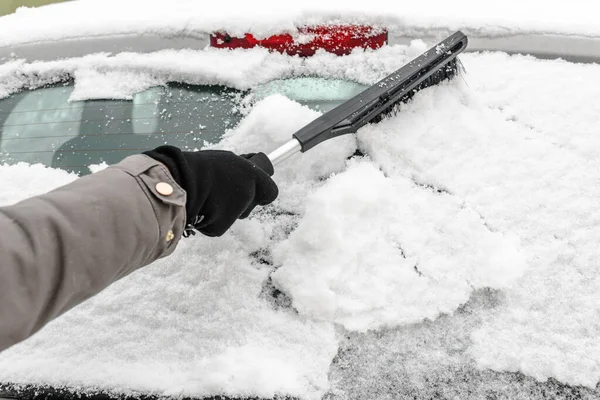 Žena čistící auto ze sněhu štětcem. Lidé ve sněhovém chladném počasí v zimě a dopravní koncepce. — Stock fotografie