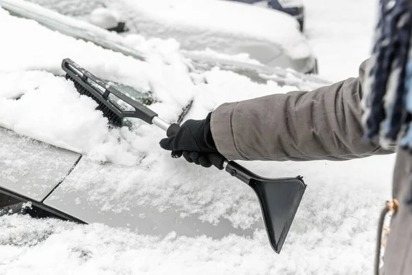 Donna che pulisce la macchina dalla neve con la spazzola. Gente con freddo nevoso in inverno e concetto di trasporto . — Foto Stock