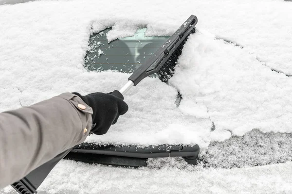 Frau reinigt Auto mit Bürste vom Schnee. Menschen bei schneereicher Kälte im Winter und Transportkonzept. — Stockfoto