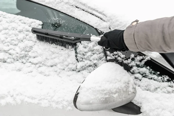 Kobieta czyści samochód ze śniegu szczotką. Ludzie w śniegu zimno pogoda w zimie i koncepcji transportu. — Zdjęcie stockowe