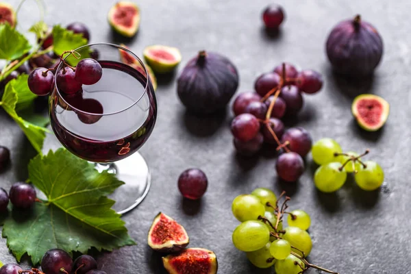 Frutas frescas e copo de vinho tinto sobre fundo escuro — Fotografia de Stock