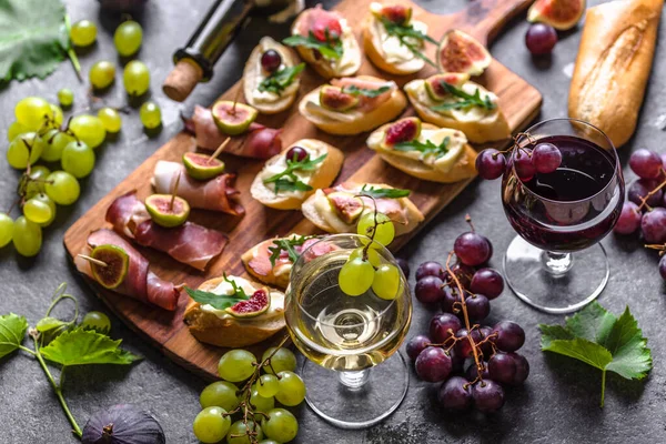 Tapas espanholas tradicionais, lanche de vinho - comida de espanha ou antipasti italiano: bruschetta com queijo, carne e frutas. Aperitivos frios e copos de vinho . — Fotografia de Stock