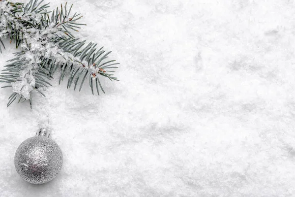 Sfondo natalizio con neve, ramo di abete e palla di vetro, design natalizio — Foto Stock