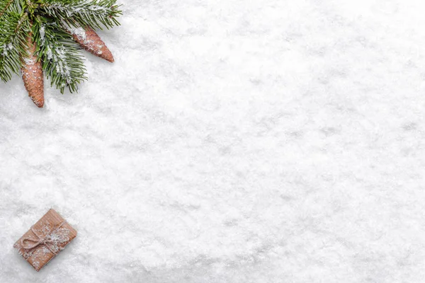 Fondo natalizio con neve, ramo di abete natalizio, pigne e scatola regalo, piatta, vista dall'alto — Foto Stock